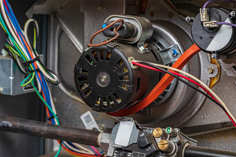 Close-up of a furnace blower motor with wiring and components